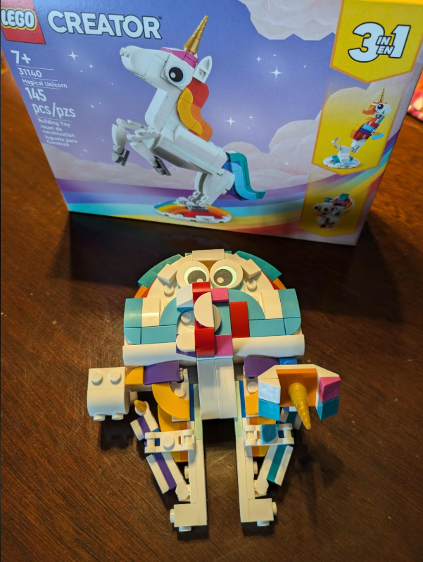 Ein bunter handteller-großer Millennium Falcon vor der Schachtel eines Einhorn-Sets.